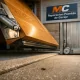 Estudio de puertas de garaje: una basculante de madera brillante y una corredera metálica, mostrando sus ventajas funcionales.